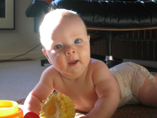 Hason fekvő mosolygó kisbaba néz a kamerába, Kép: wikipedia