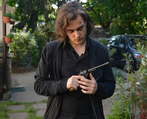 Jelenetfotó, fiatal férfi nézi a kezében lévő pisztolyt, Kép: HBO 