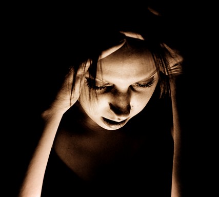 Beteg nő fejét kezébe hajtja, arcát alulról világítja meg a fény, Kép: wikimedia
