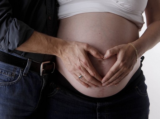 Terhes nő hasa, férje átkarolja, kettőjük keze szivet formál a nő hasán, Kép: pixabay