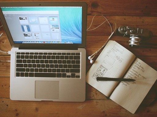 Fentről fényképezve egy asztal, rajta egy laptop, egy fényképezőgép és egy jegyzetfüzet ceruzával, Kép: pixabay