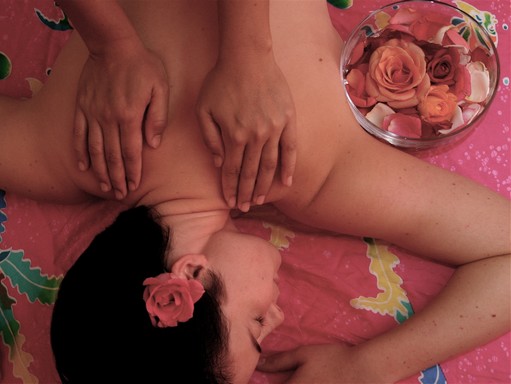 Egy hölgyet maszíroznak, hajában rózsa, mellette tálban rózsaszirmok, Kép: wikimedia
