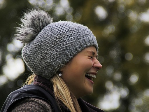 Nagyon nevető lány oldalról, fején szürke téli kötött sapka, Kép: pixabay 