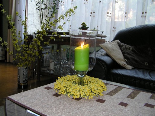 Tavaszi virágkoszorú a dohányzó asztalon, középen üvegpohárban gyertya, Kép: László Márta