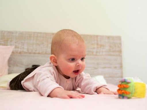 Csecsemő hasal, kapaszkodik egy színes játékért, Kép: pixabay