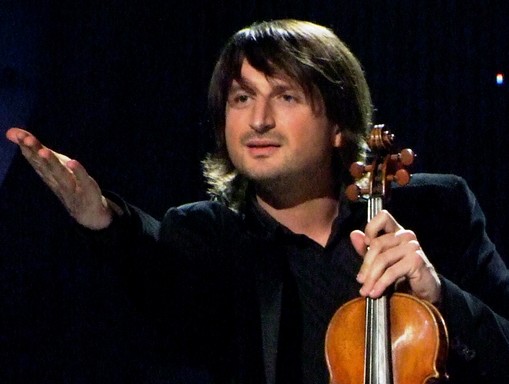 Edvin Marton egyik kezében hegedű, a másikkal a közönségre mutat, Kép: wikimedia